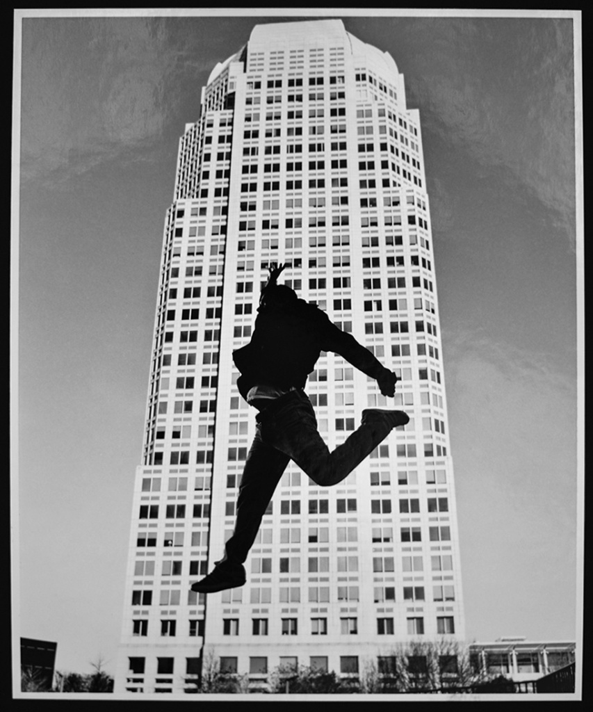 Allison_Isley image of silhouette of person jumping in front of a tall office building.